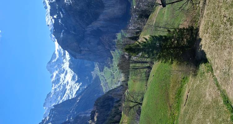 Picos alpinos coronados de nieve se alzan sobre un valle verde y exuberante salpicado de pueblos y acantilados