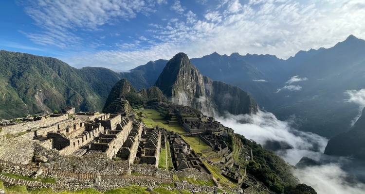 Iconic aerial view of Machu Picchu’s stone terraces rising above clouds and Andean peaks.