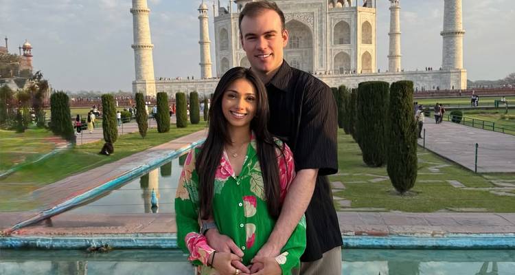 Couple debout devant le bassin réfléchissant avec le Taj Mahal qui s'élève majestueusement derrière eux.