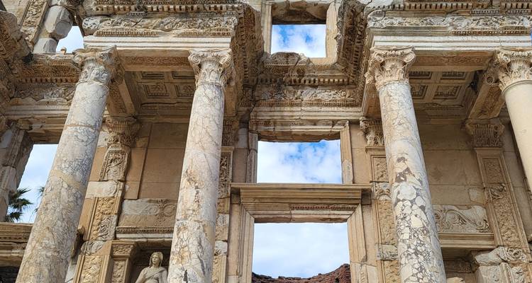 Colonnes de marbre détaillées et sculptures ornementales de la bibliothèque de Celsus à Éphèse contre le ciel.