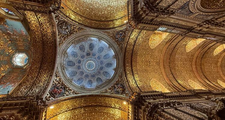 Techo dorado ornamentado de iglesia con una cúpula estrellada azul como pieza central enmarcada por tallados intrincados.