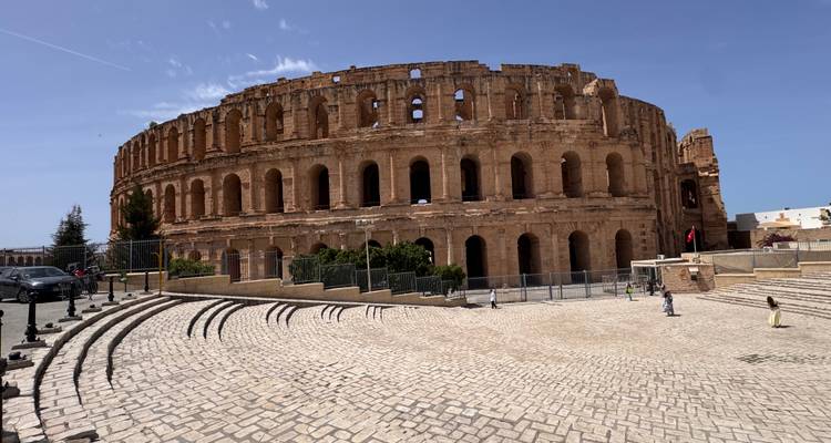 El gran anfiteatro romano de El Jem domina la plaza bajo un cielo azul despejado.