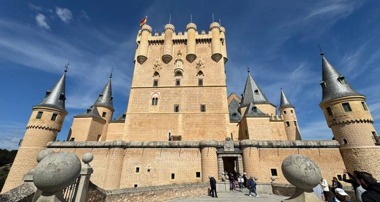 Las torres de cuento de hadas del Alcázar de Segovia se alzan contra un cielo azul intenso.