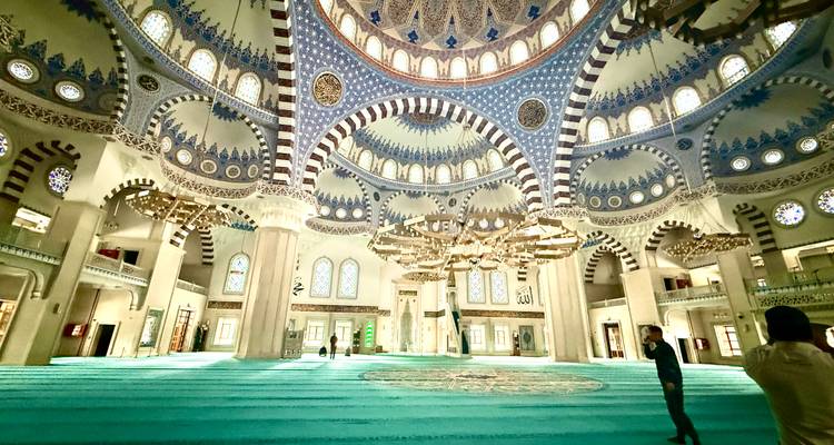 Opulent gestaltetes Inneres der Zentralmoschee von Duschanbe mit türkisfarbenen Teppichen und kunstvoll verzierten Kuppeln.