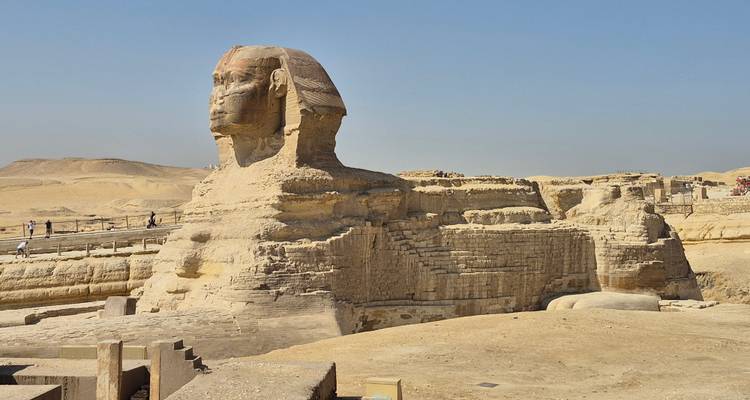 Profil latéral du Grand Sphinx avec son corps monumental en calcaire contre un ciel dégagé.
