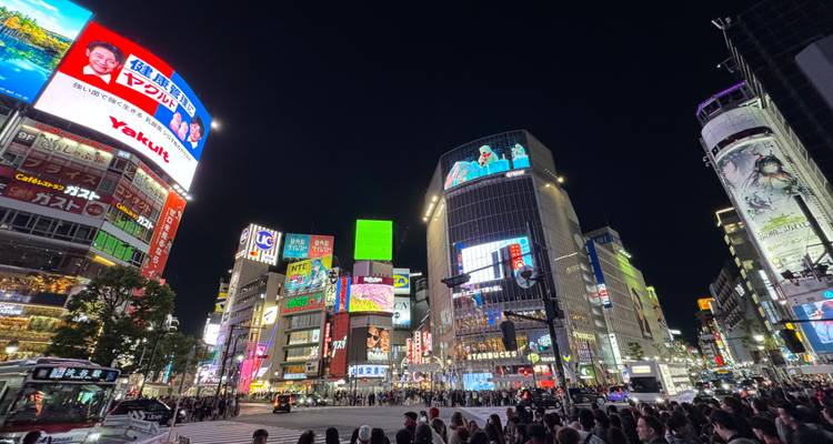 Vista nocturna del abarrotado Shibuya Crossing con brillantes carteles de neón y multitudes