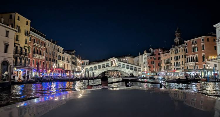 El icónico Puente de Rialto y las luces brillantes reflejadas en el Gran Canal por la noche