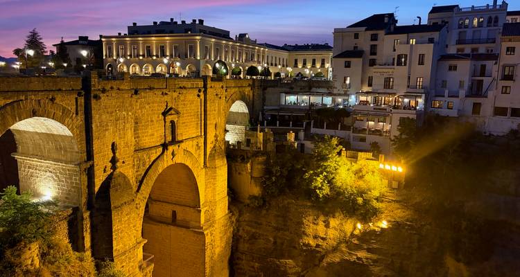 Nachtview van de Puente Nuevo brug in Ronda dramatisch verlicht boven de kloof met stadslichten.