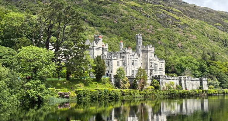 Schloss aus der viktorianischen Ära, perfekt in einem stillen See inmitten grüner Hügel gespiegelt