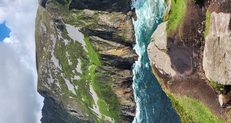 Dramatic sea cliffs with green slopes dropping into turquoise Atlantic waters