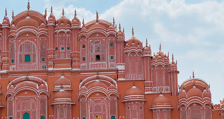 Close-up of the richly ornamented pink façade of Jaipur’s Hawa Mahal set against a blue sky.