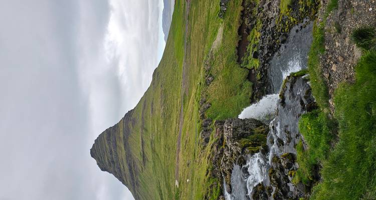 Iconic Kirkjufell mountain with cascading stream and small waterfall in foreground