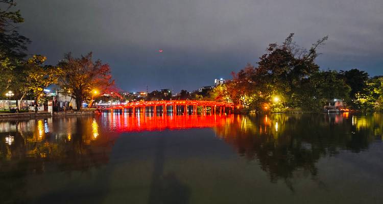 Vue nocturne du pont rouge illuminé The Huc de Hanoï se reflétant sur le lac Hoan Kiem.