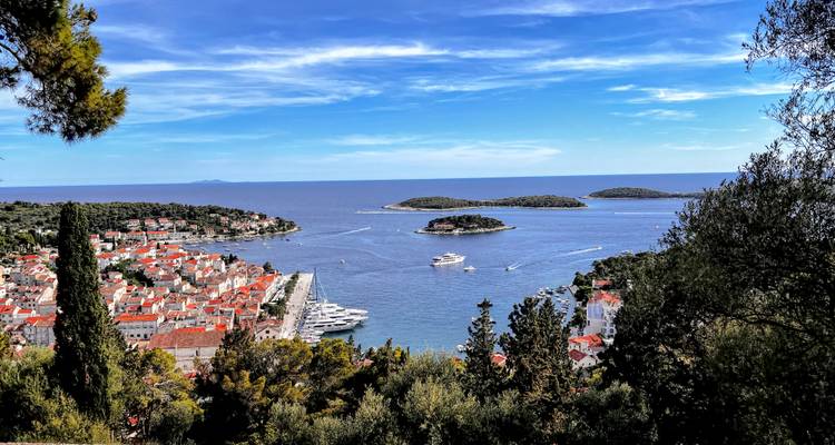 Aerial view of Hvar town’s red rooftops, marina and surrounding islets under a vivid blue sky