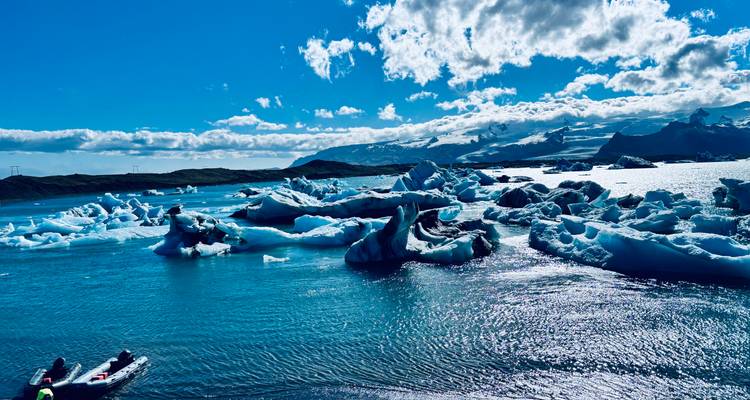 Leuchtend blauer Gletschersee mit kunstvoll geformten Eisbergen unter einem sonnigen Himmel.