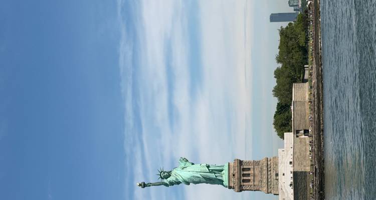 Iconic Statue of Liberty rises above New York Harbor under a clear sky.