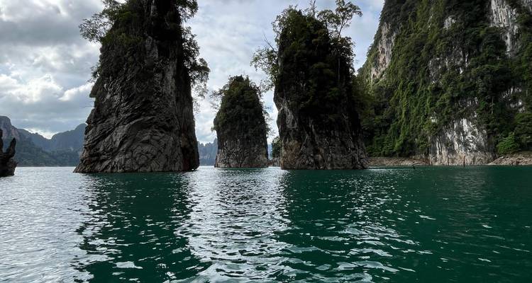 Towering limestone karst pillars rise from emerald water in Khao Sok National Park