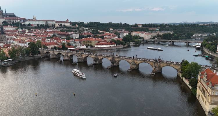 vue aérienne du pont Charles enjambant la Vltava avec le château de Prague et les bateaux en dessous