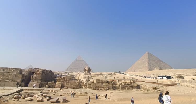 Panoramablick auf das Giza-Plateau mit den Großen Pyramiden, der Sphinx und verstreuten Touristen.