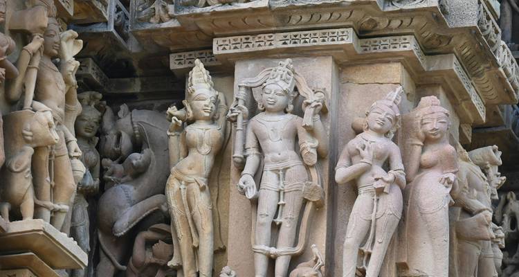 Detailed close-up of intricately carved sandstone figures adorning the façade of an ancient Khajuraho temple.
