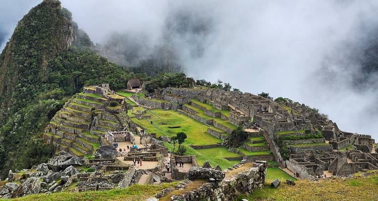 De terrasgewijze ruïnes van Machu Picchu verschijnen uit zwevende wolken met de uitstekende piek van Huayna Picchu.