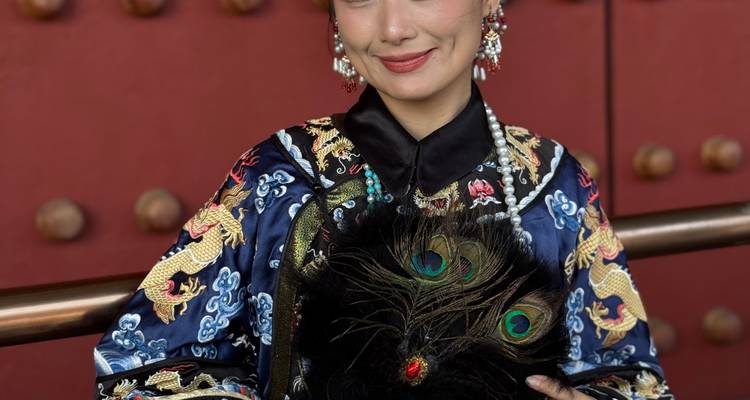 Portretfoto in studiostijl van een vrouw in prachtige Qing-kledij met een pauwveer waaier in haar handen.