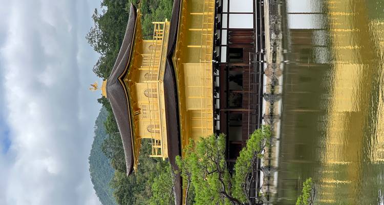 Le temple emblématique de Kinkaku-ji recouvert de feuilles d'or se reflétant dans un étang tranquille avec des collines boisées en arrière-plan.