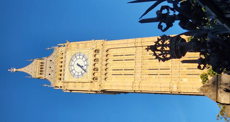Der ikonische Elizabeth Tower mit seinem leuchtenden Ziffernblatt gegen einen tiefblauen Himmel während des warmen Abendlichts.