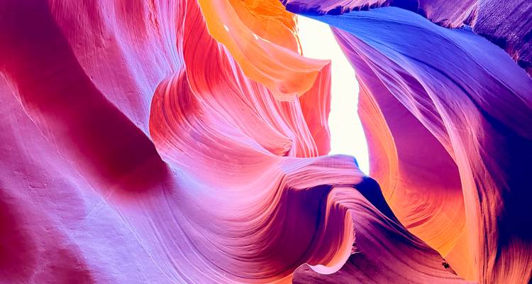 Les ondulations de grès multicolore se déploient avec élégance vers une ouverture lumineuse en surplomb.
