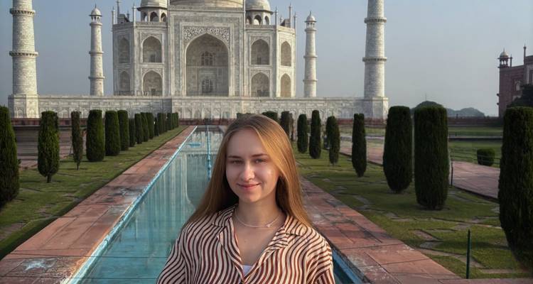 Young woman poses in front of the reflecting pool and pristine white marble Taj Mahal.