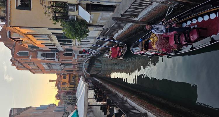Sereno canal veneciano al atardecer con gondolero navegando bajo una luz dorada y suave.