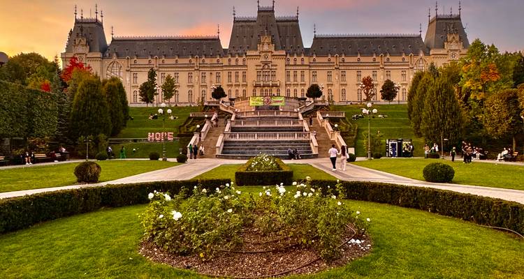 Palacio de la Cultura en Iași al atardecer con jardines bien cuidados y visitantes paseando.