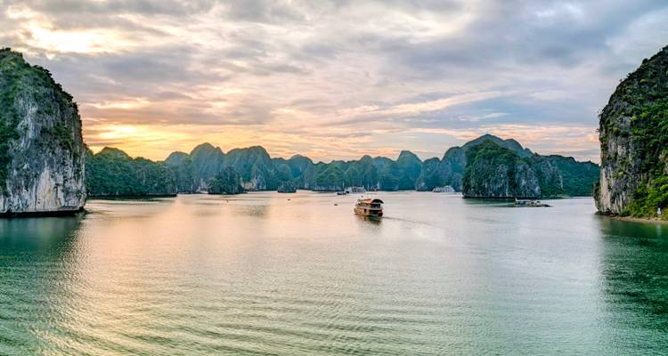 Panorama pittoresque des eaux d'émeraude et des pics calcaires de la baie d'Ha Long au coucher de soleil doré