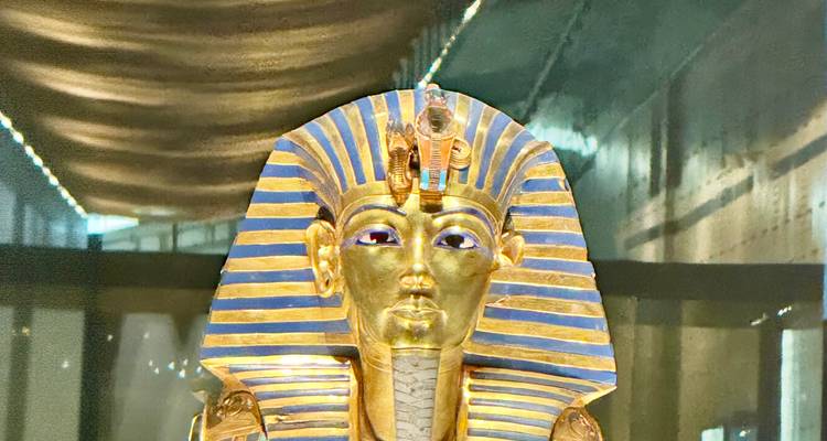Iconic gold funerary mask of Tutankhamun shines under museum lights.