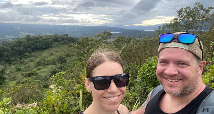 Couple posing with a panoramic view of forested hills.