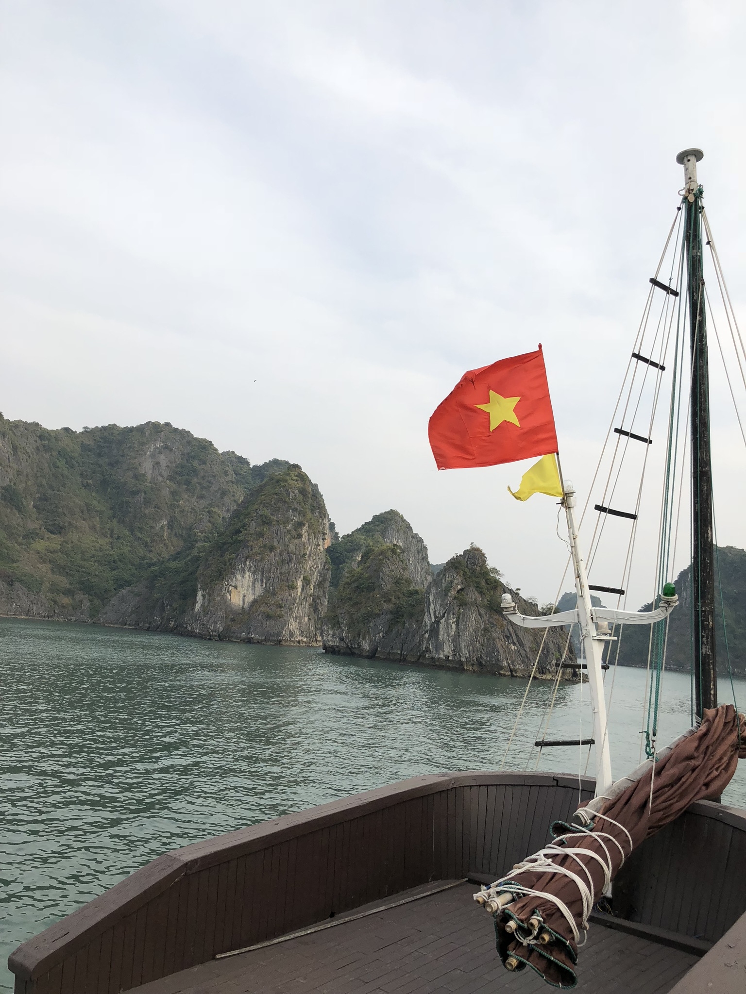 Vietnamese flag flying on a boat in front of Halong Bay.