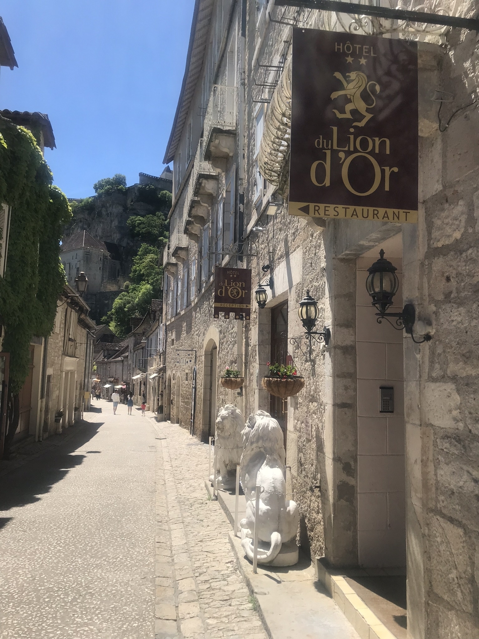 Historic street with stone buildings and lion statutes.