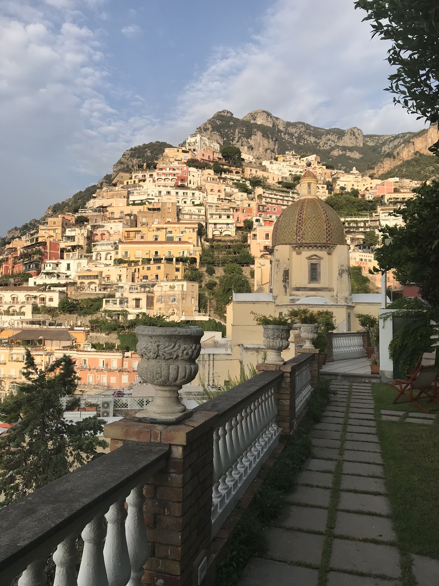 Positano cityscape with colorful hillside buildings and a dome.