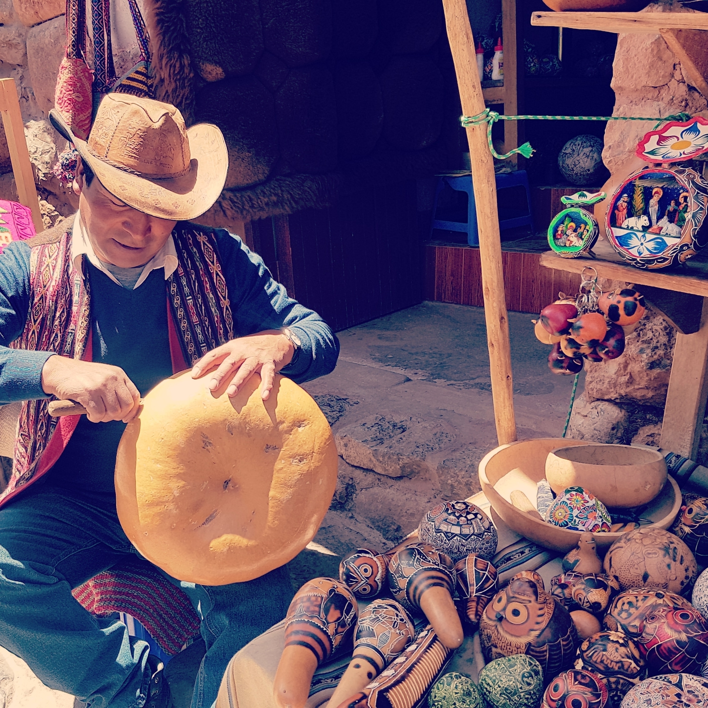 Artisan carving a large wooden object in a market setting.