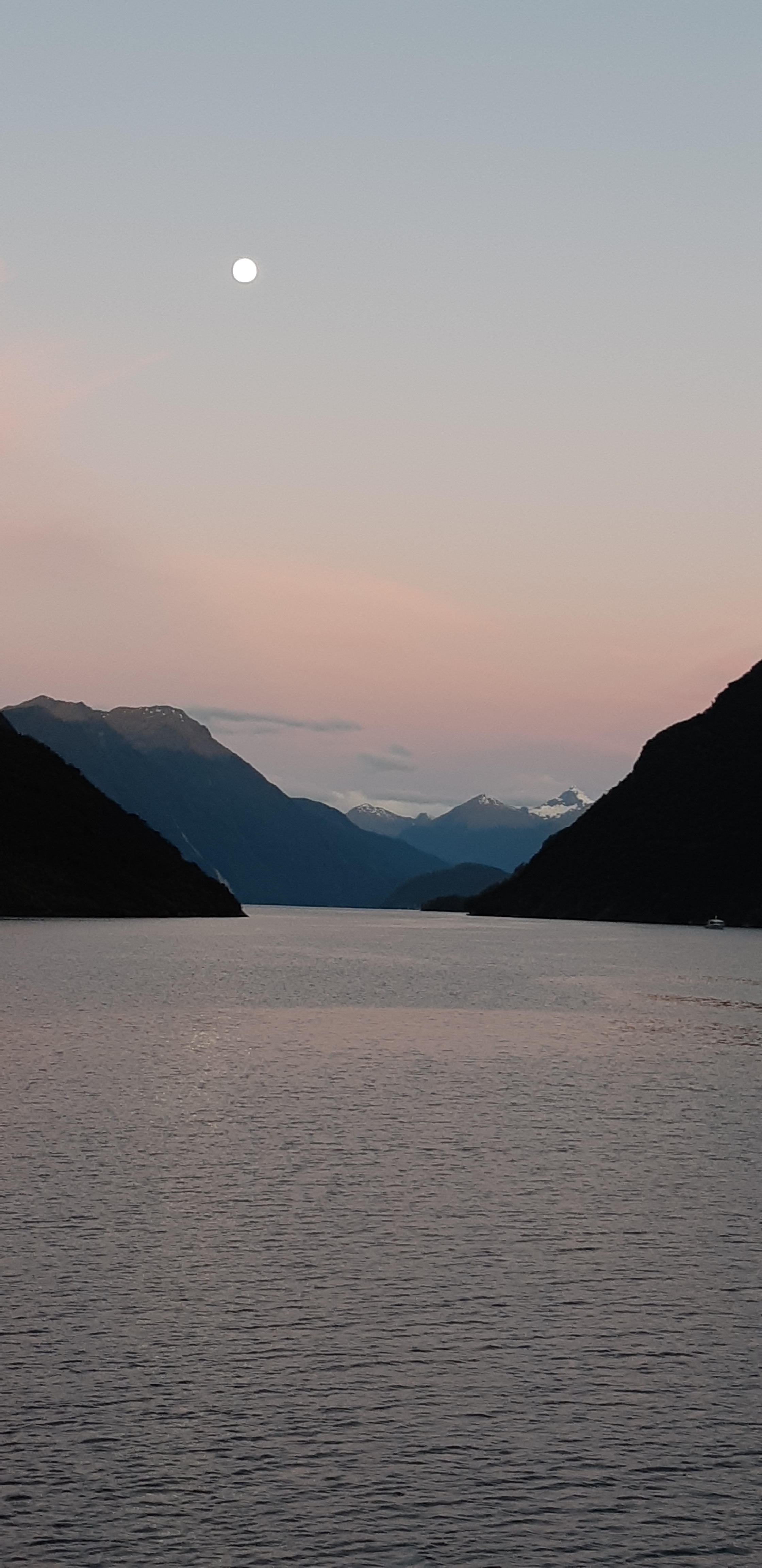 Mountainous landscape image with a body of water at dawn.