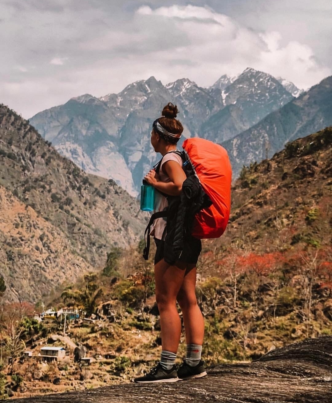 Person with large backpack standing in a mountainous landscape.