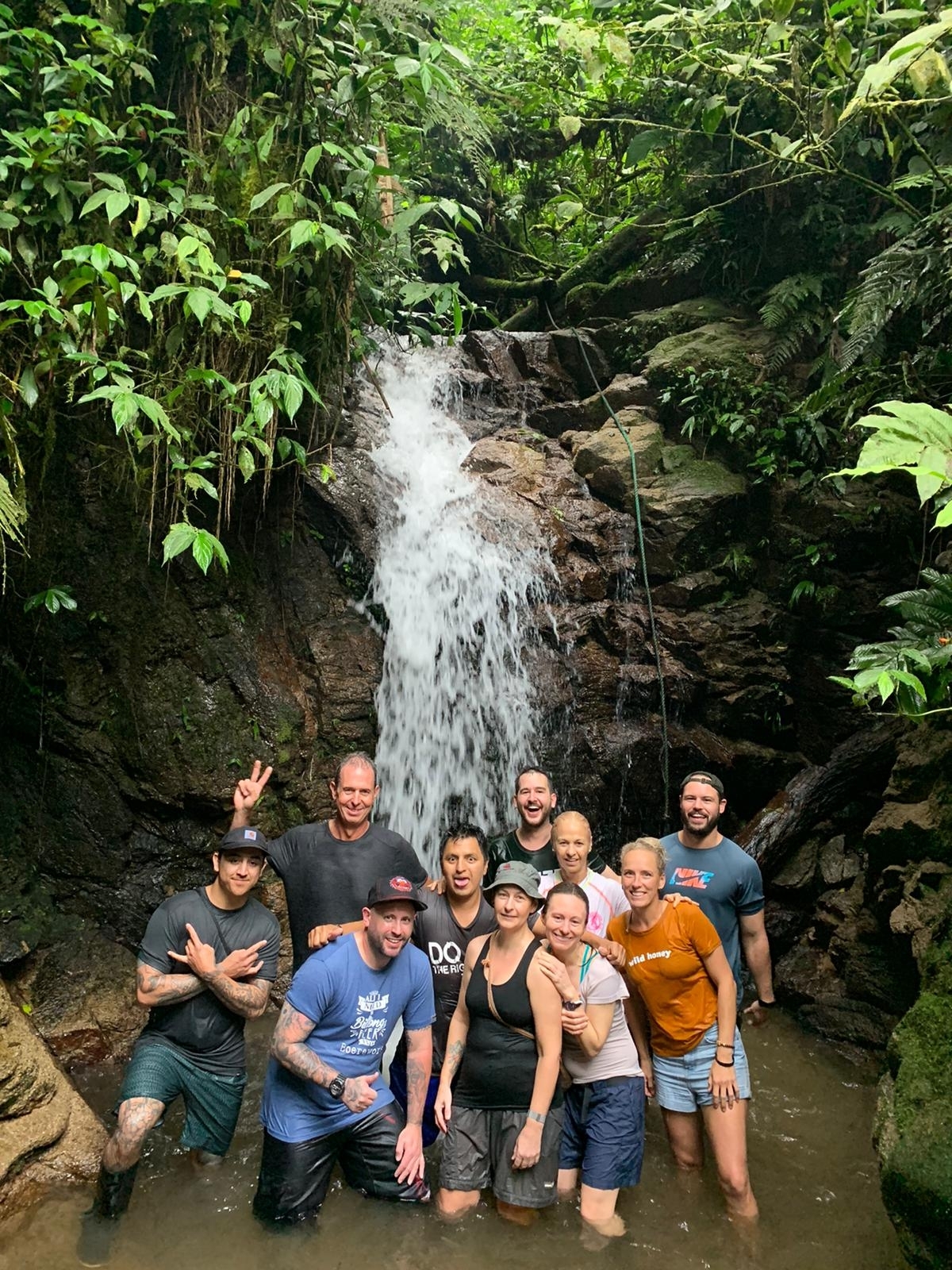 Group standing in front of a waterfall in a jungle setting.