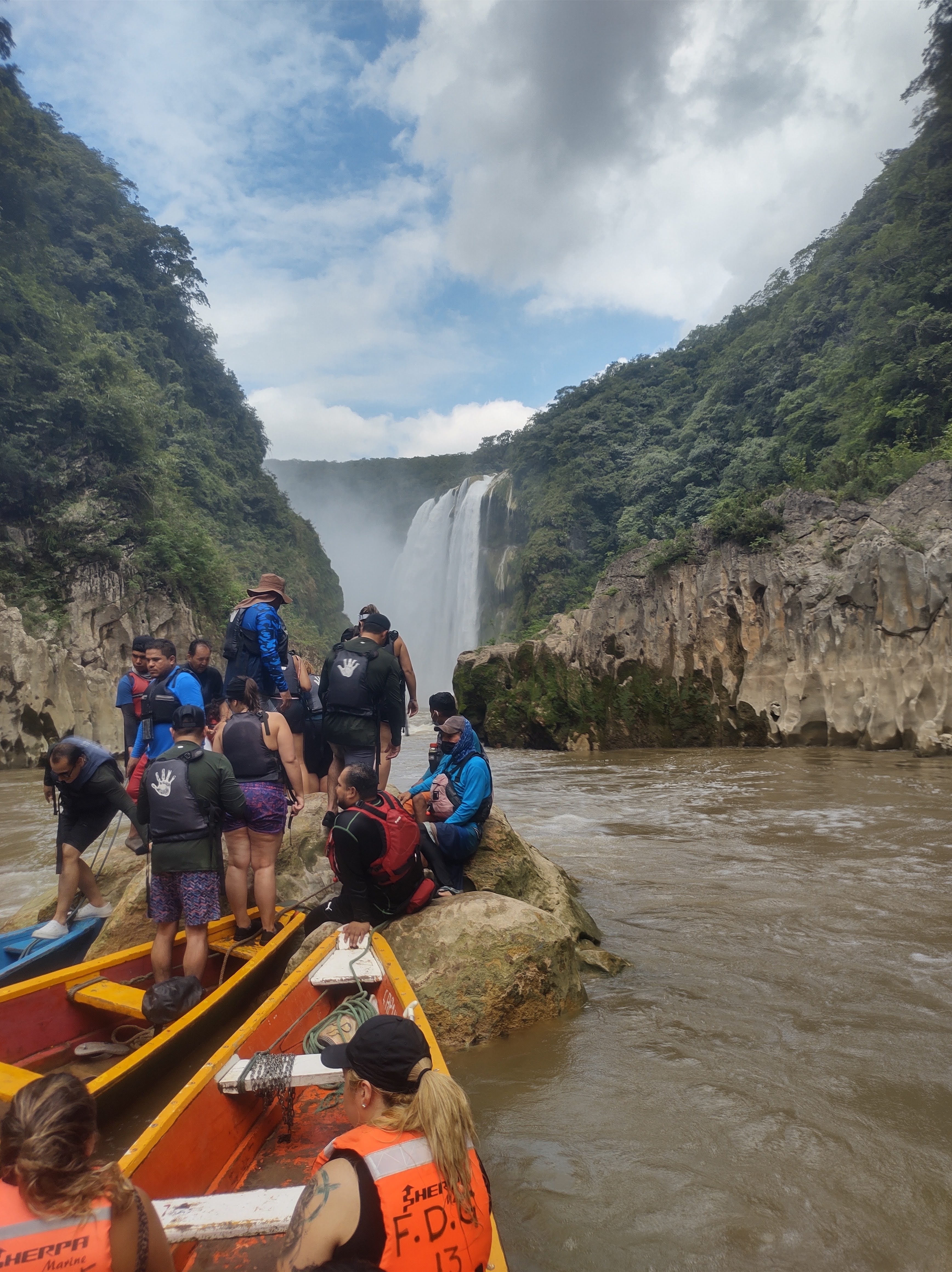 Group of people at the base of a large waterfall.
