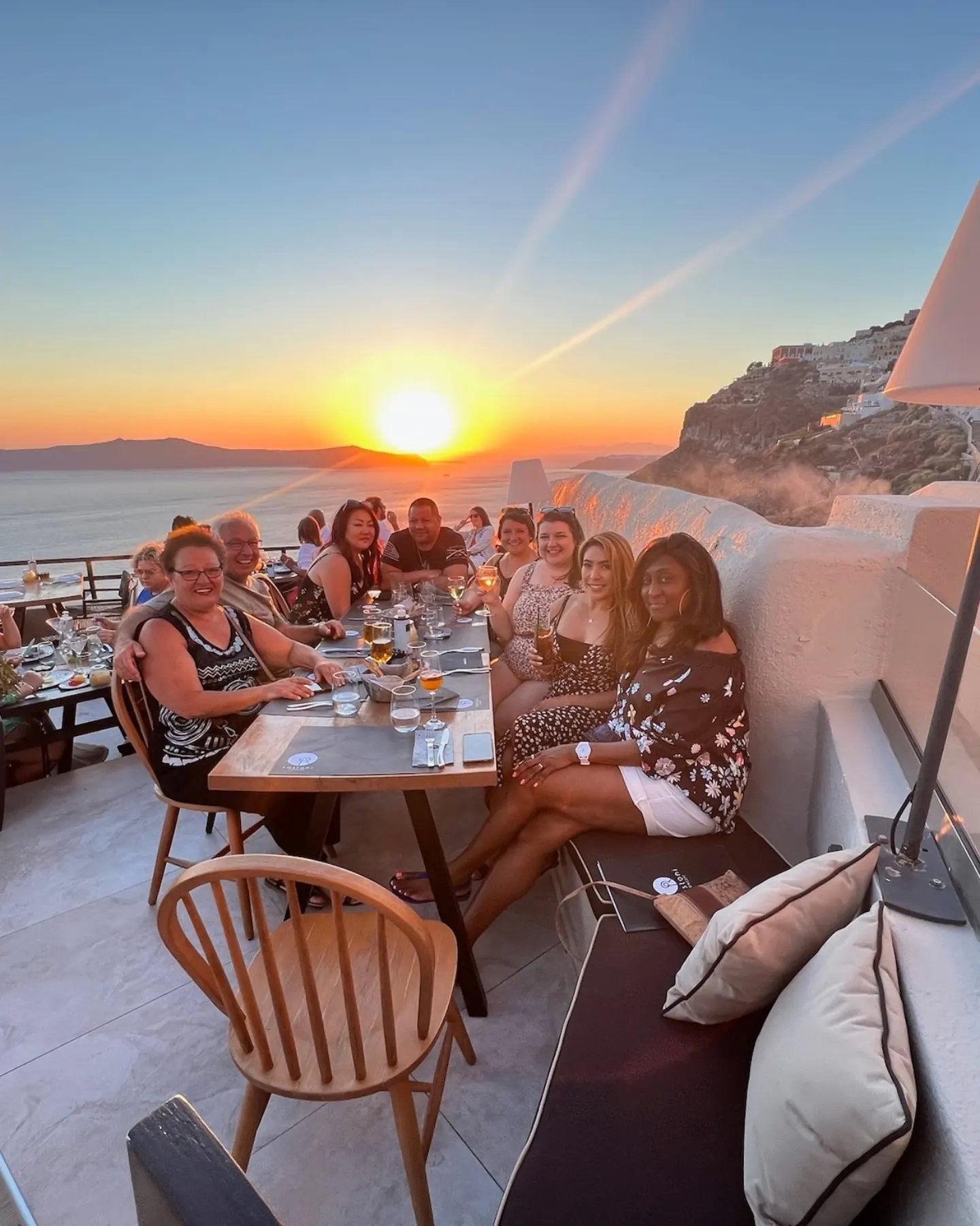 Group of people seated at a table enjoying dinner with sunset view.