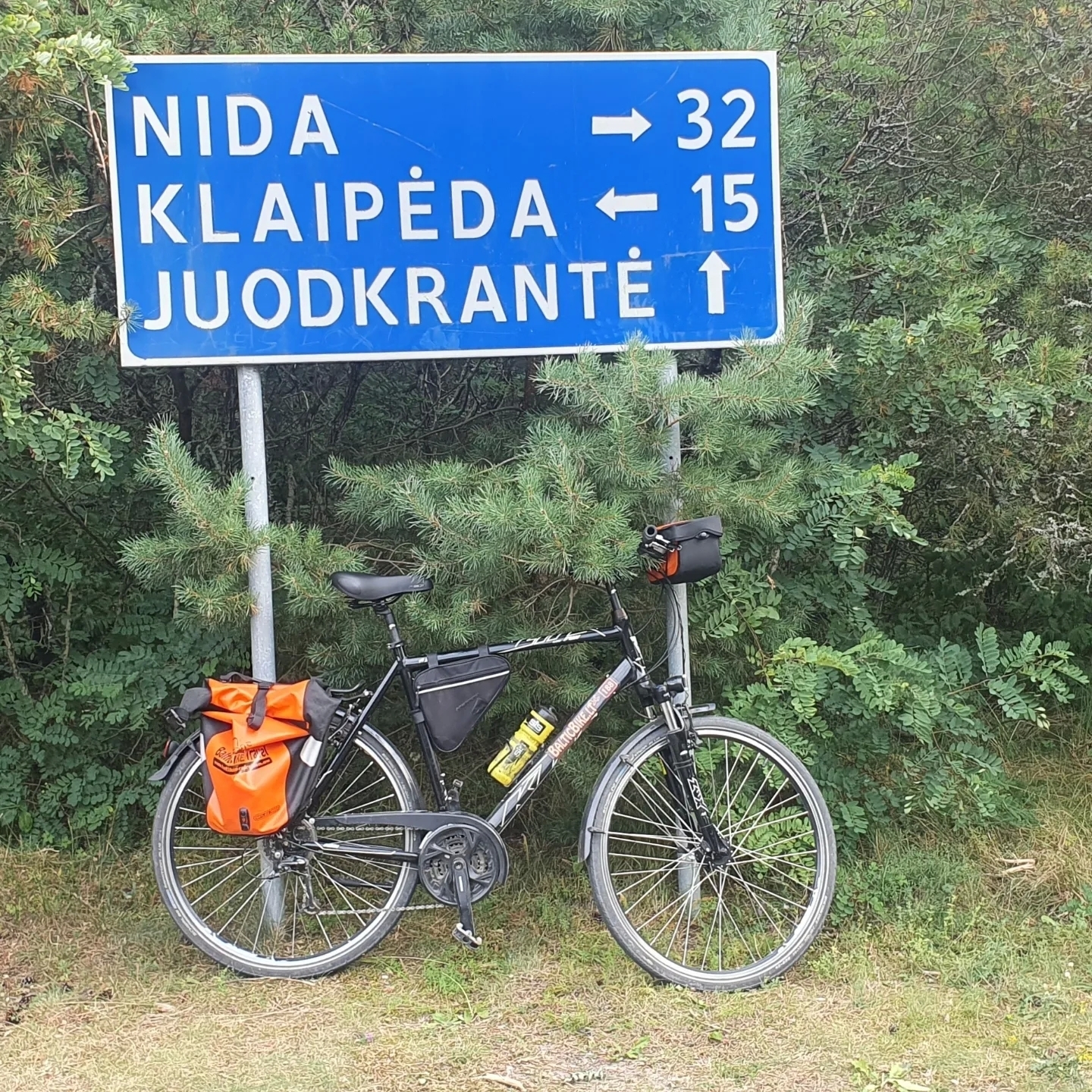 A bicycle parked by a sign pointing to Juodkrante.