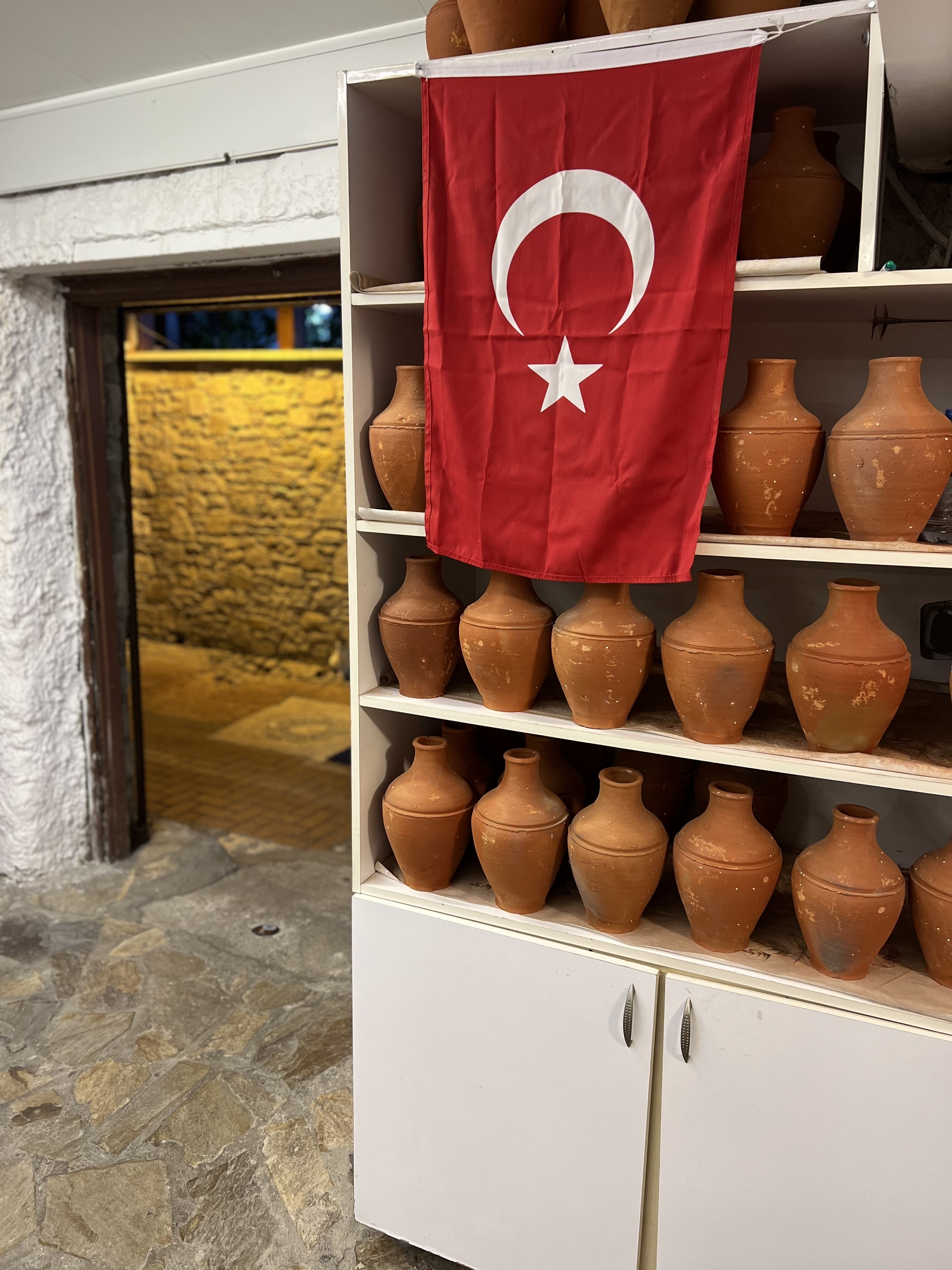 A display of clay pots with a Turkish flag in a shop.