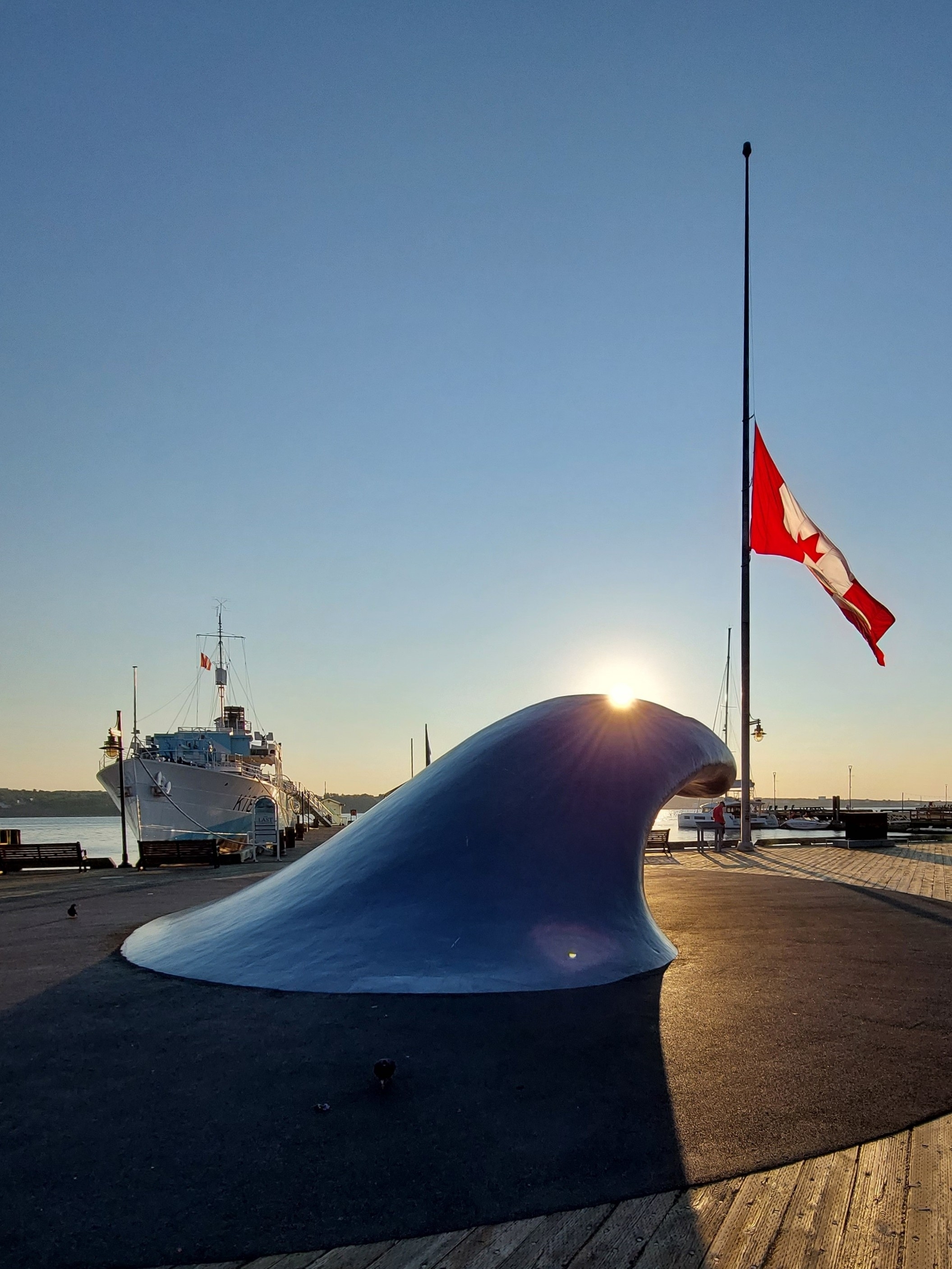 Ship and Canadian flag on a waterfront during sunset.