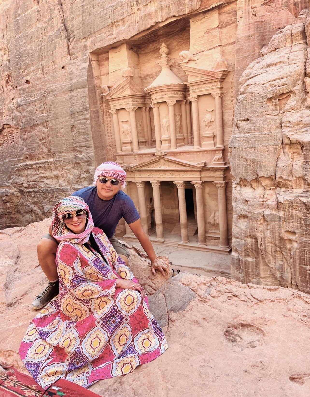 Two people posing with the iconic rock-cut architecture of Petra.