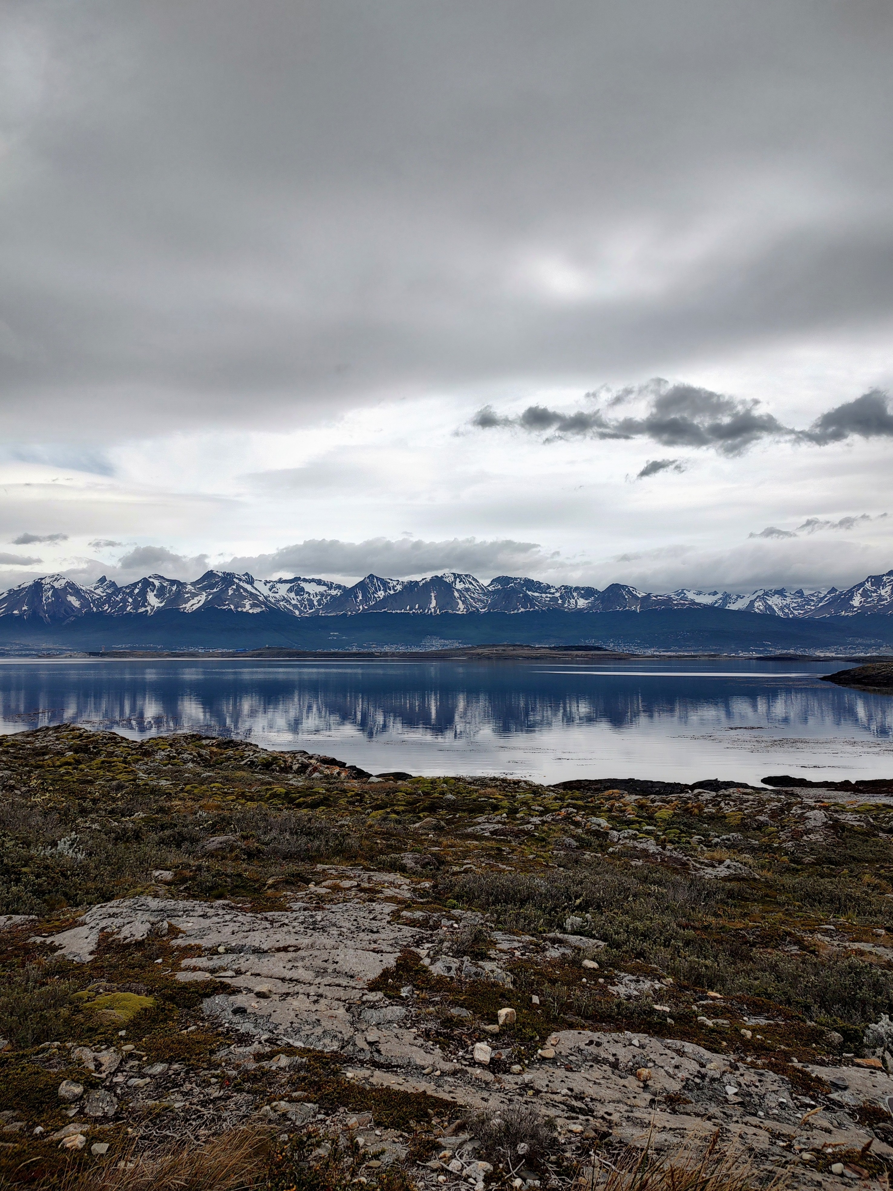 Mountain range with snow caps reflected in a calm lake.