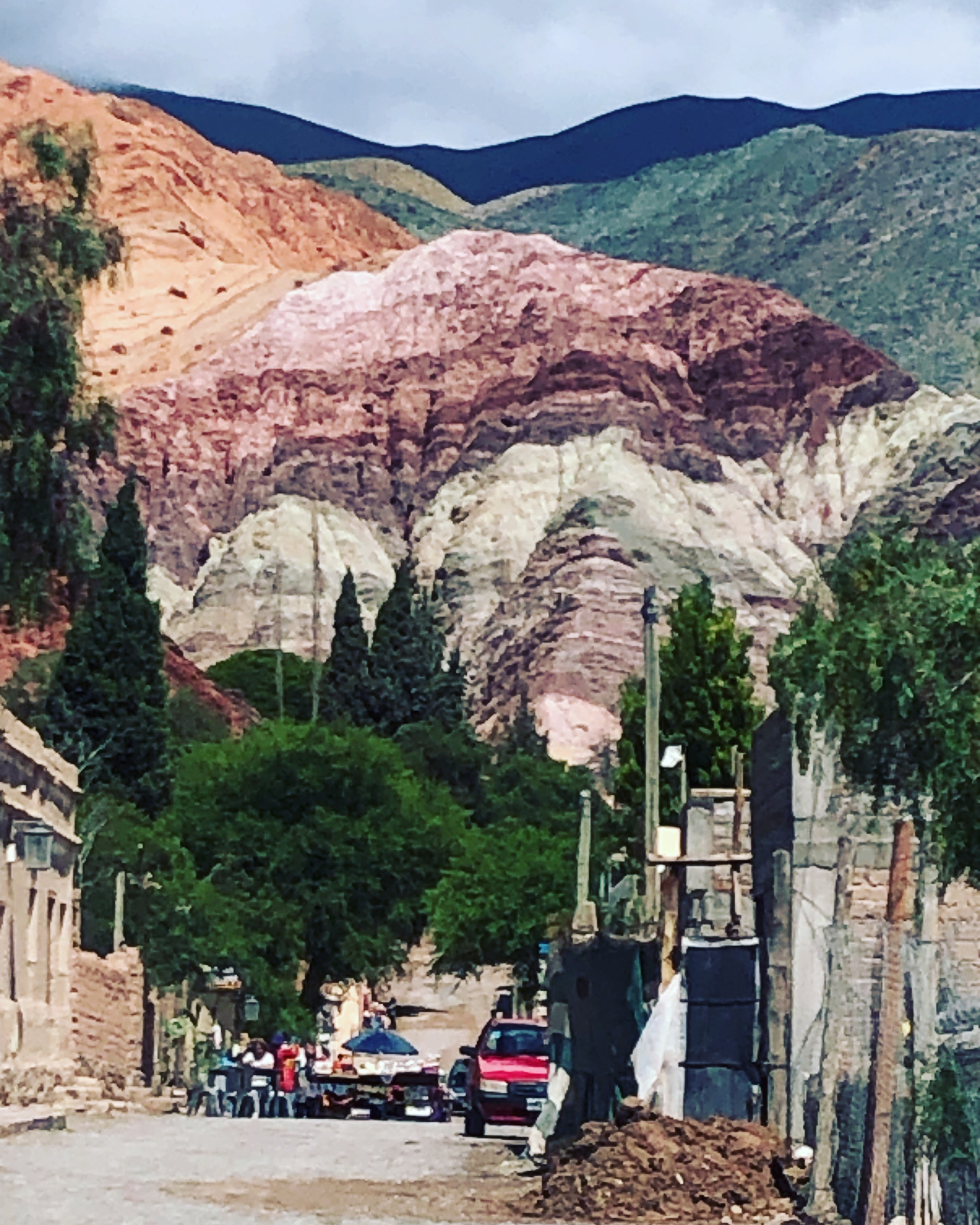 Colorful layered mountains with greenery at the base, likely in Purmamarca.